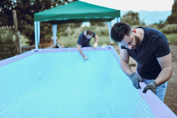istock Two Male Workers Setting Up Swimming Pool In Backyard 1035788648