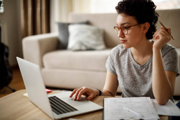 young woman working at home - paper document notebook laptop imagens e fotografias de stock