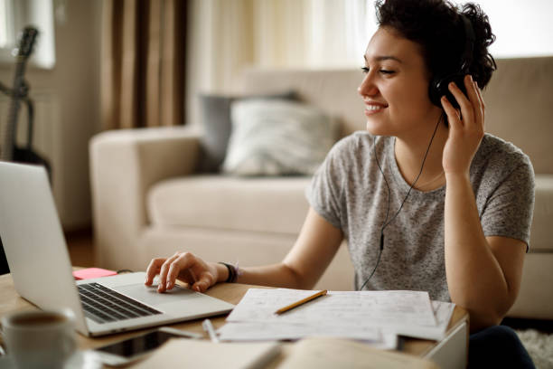 mujer joven con portátil y escuchar música en casa - hot drink audio fotografías e imágenes de stock