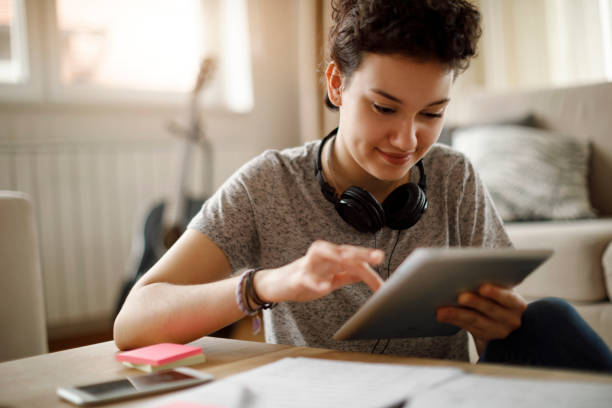 smiling young woman using digital tablet at home - muse indoors lifestyles education imagens e fotografias de stock