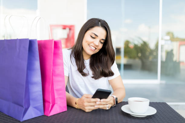 istock Beautiful Female Shopper Texting On Smartphone In Cafe 1035801592