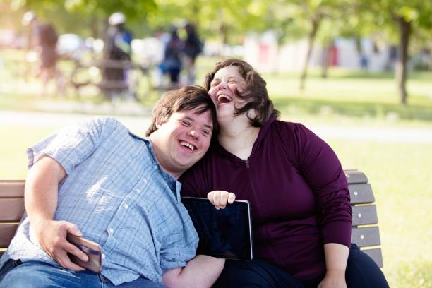 Couple with Down Syndrome working doing selfie with mobile phone Couple in love of 26 years old Down Syndrome in a park in Montreal doing selfie with mobile phone. They are learning to live independently.  Color and horizontal photo was taken in Quebec Canada. disabled adult stock pictures, royalty-free photos & images
