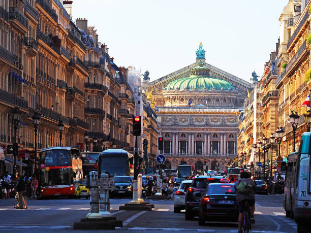 The facade of the Palais Garnier opera house. National Academy of Music. People walking around, traffic on the street. Square Place de l'Opera, avenue de l'Opera. Sunset, crosswalk Paris, France - June, 2018: The facade of the Palais Garnier opera house. National Academy of Music. People walking around, traffic on the street. Square Place de l'Opera, avenue de l'Opera. Sunset, crosswalk place de lopera stock pictures, royalty-free photos & images