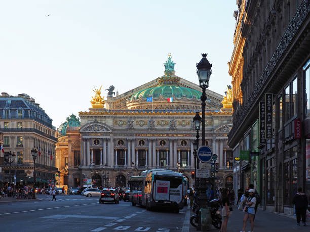 The facade of the Palais Garnier opera house. National Academy of Music. People walking around, traffic on the street. Square Place de l'Opera, avenue de l'Opera. Sunset Paris, France - June, 2018: The facade of the Palais Garnier opera house. National Academy of Music. People walking around, traffic on the street. Square Place de l'Opera, avenue de l'Opera. Sunset place de lopera stock pictures, royalty-free photos & images