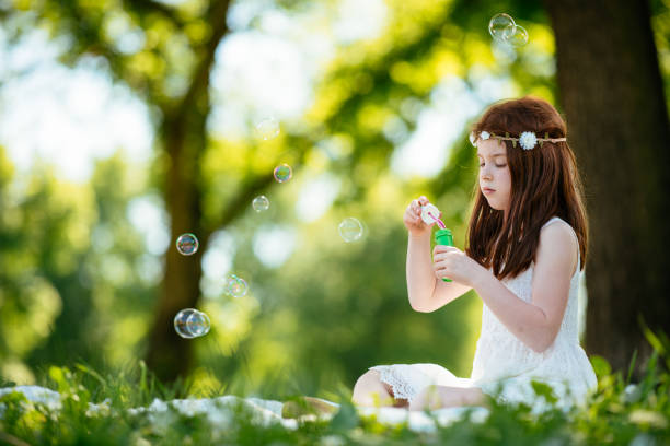 Beautiful little girl blowing bubbles. Shallow DOF. Developed from RAW; retouched with special care and attention; Small amount of grain added for best final impression. 16 bit Adobe RGB color profile.