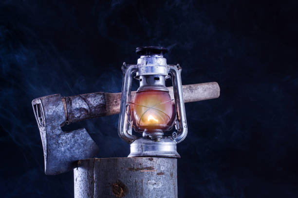 istock Old gas lamp burning and ax in lumber log 1035827232