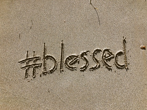 Blessed message with a modern social media hashtag twist written in the sand on the beach