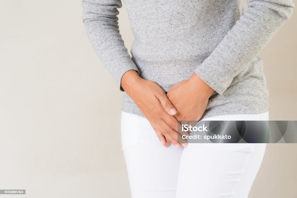 Young woman having painful stomachache with hands holding pressing her crotch lower abdomen. Medical or gynecological problems, healthcare concept Women Stock Photo