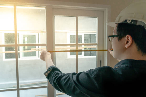 istock Young Asian engineer or worker with safety helmet and eyeglasses using tape measure for measuring window at construction site. House builder concept. Architecture and engineering of housing project 1035887210