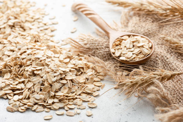 avena arrotolata, spighe di grano e cucchiaio di legno - oat oatmeal rolled oats oat flake foto e immagini stock