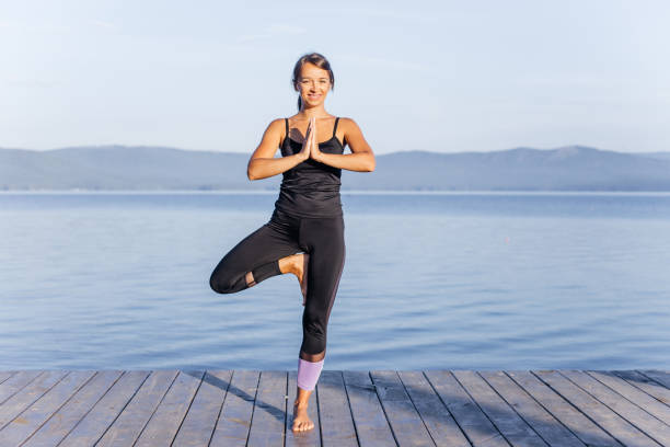istock Young attractive smiling woman practicing yoga on a lake 1035950224