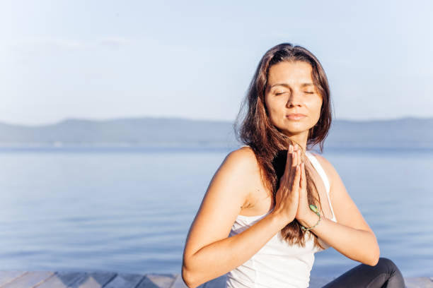 istock Young attractive smiling woman practicing yoga on a lake 1035950338