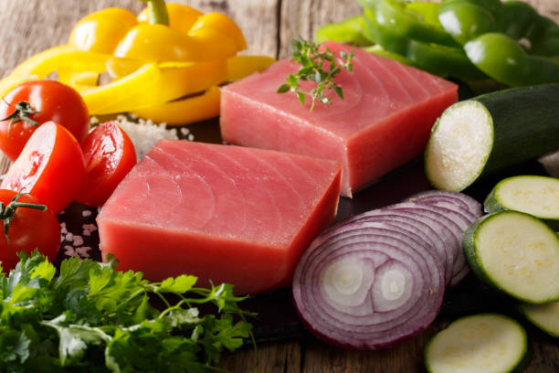 filete de atún crudo con pimienta, cebollas, tomates, calabacines y verdes close-up. horizontal - tuna tuna steak raw freshness fotografías e imágenes de stock