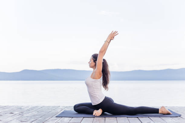 istock Young attractive smiling woman practicing yoga on a lake 1035952670