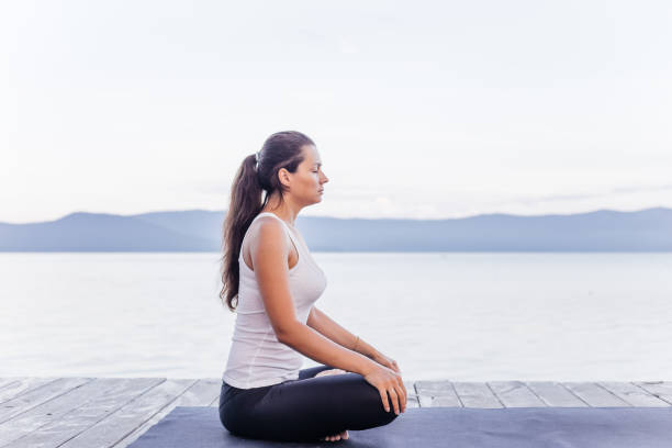 istock Young attractive smiling woman practicing yoga on a lake 1035952724