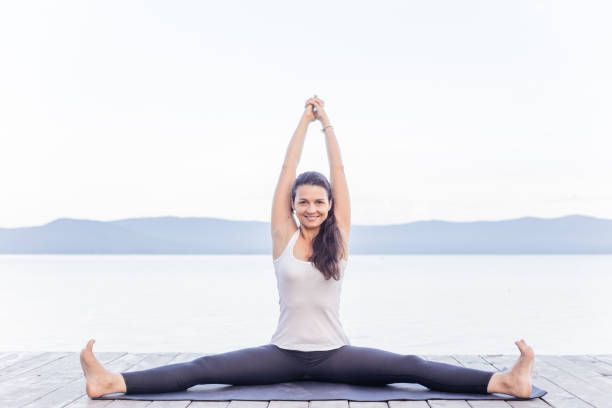 istock Young attractive smiling woman practicing yoga on a lake 1035952896