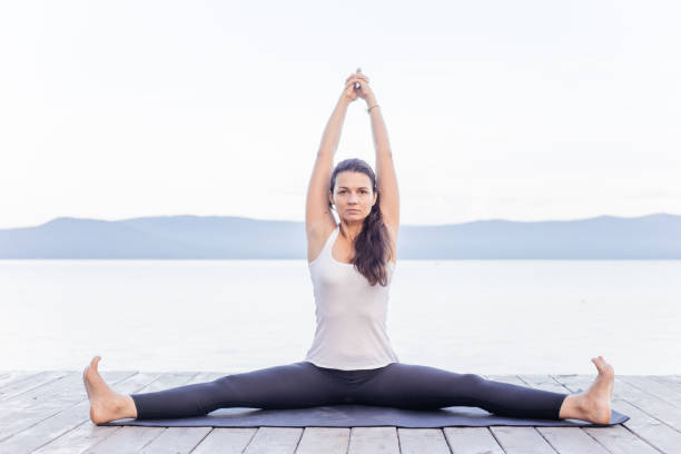 istock Young attractive smiling woman practicing yoga on a lake 1035952934