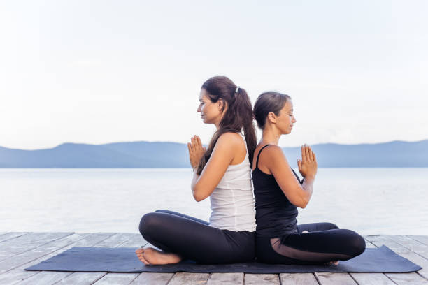istock Young attractive smiling women practicing yoga on a lake 1035953162