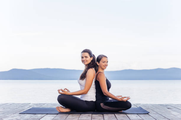 istock Young attractive smiling women practicing yoga on a lake 1035953172