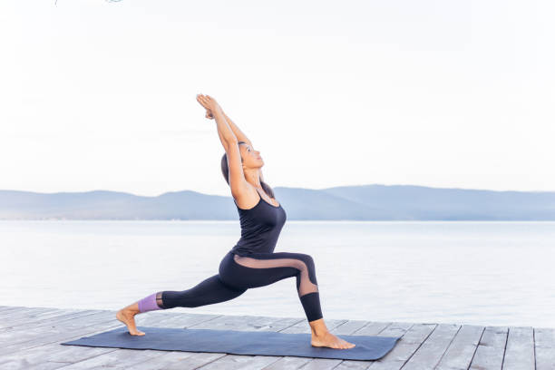 istock Young attractive smiling woman practicing yoga on a lake 1035953234