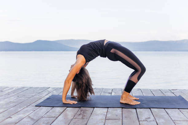 istock Young attractive smiling woman practicing yoga on a lake 1035953356