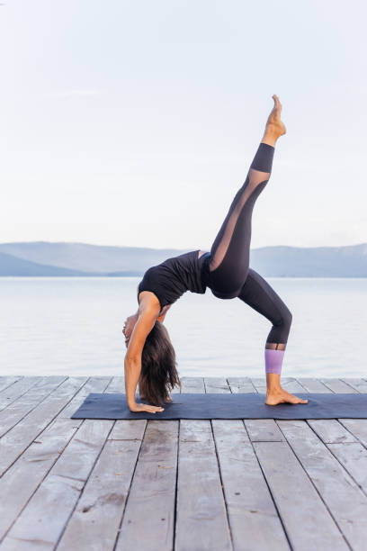 istock Young attractive smiling woman practicing yoga on a lake 1035953388
