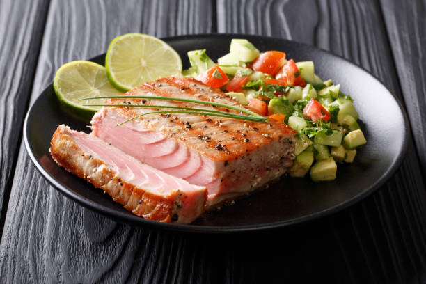 コショウ、アボカドきゅうりのサルサのクローズ アップのマグロ ステーキをグリルしました。水平方向 - peppered tuna ストックフォトと画像