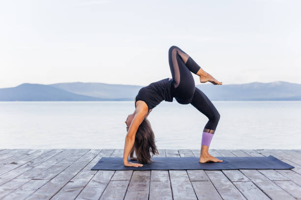 istock Young attractive smiling woman practicing yoga on a lake 1035953646