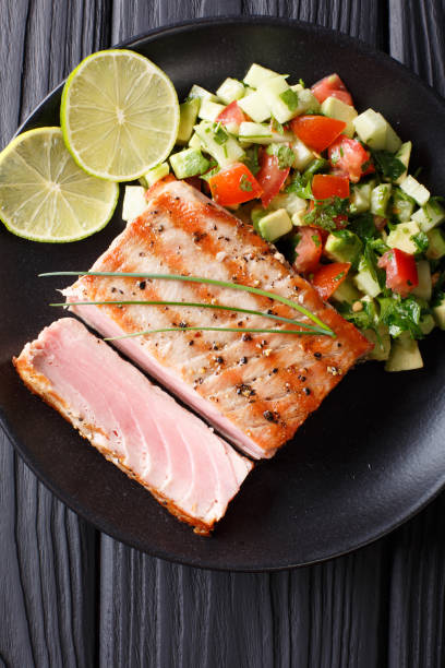 istock Lime Grilled Tuna with Avocado Cucumber Salsa closeup on a plate. Top view from above vertical 1035956766