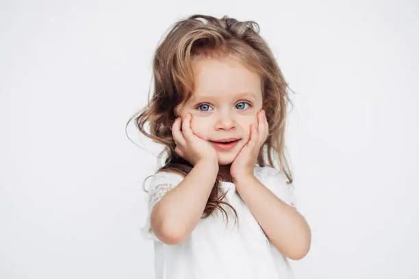 Photo of Cute little girl in white dress smiling on camera