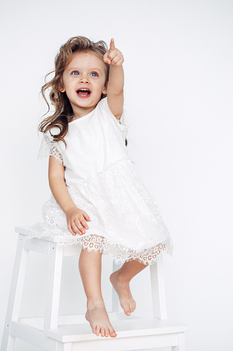 Cute little girl in white dress smiling on camera