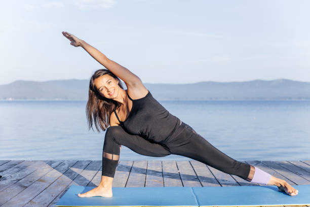 istock Young attractive smiling woman practicing yoga on a lake 1035967852
