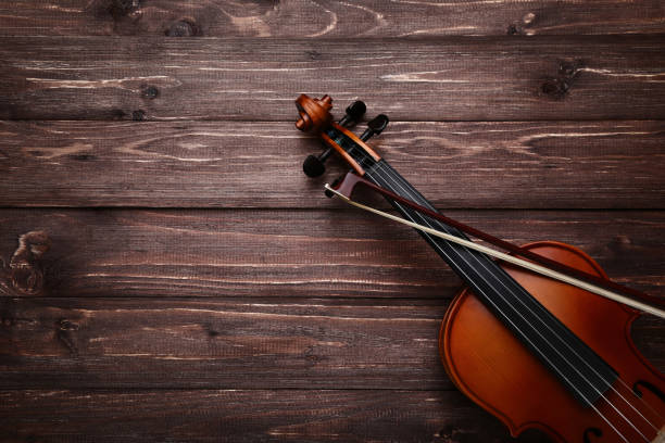 istock Violin with bow on brown wooden table 1035981852