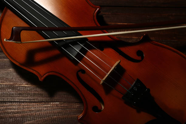 istock Violin with bow on brown wooden table 1035982116