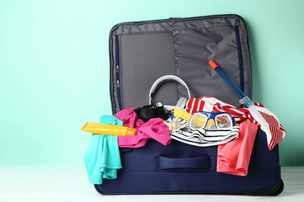 istock Opened suitcase with clothes, headphones, camera and diving mask 1035983630