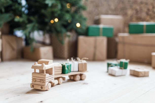 istock Wooden toy car with christmas gift boxes on top. Selective focus on car 1035984610