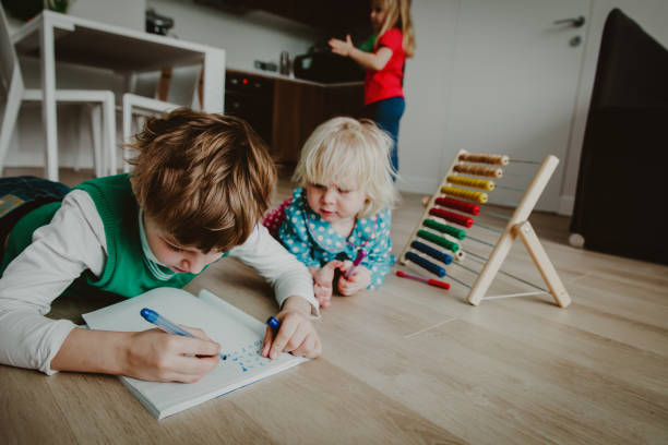 istock difficult homework- boy try to write numbers and count while other kids play around 1035985094