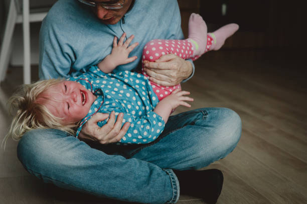 difficult parenting - dad trying to comfort shouting crying child stock photo