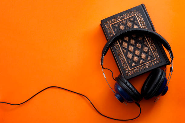 headphones and a vintage book against an orange background - hardcover book audio imagens e fotografias de stock