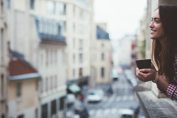 istock Relaxed woman drinking coffee on the window in Paris 1035992134
