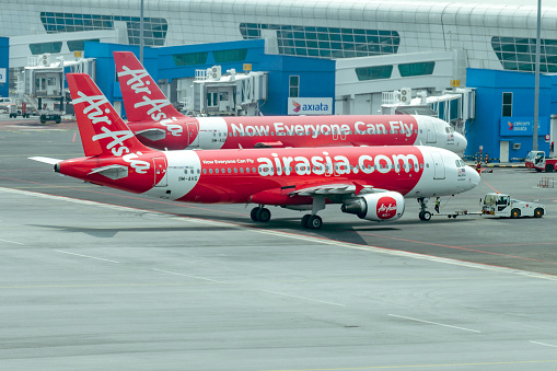 Malaysia, Kuala Lumpur International Airport, 04-03-2018:  Airplane by Airasia airline is towed to a parking lot with aircraft towing tractors. Airport daily routine close up.