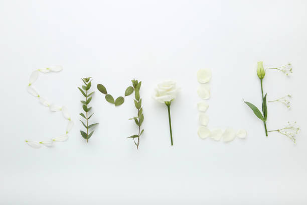 istock Inscription Smile by flowers and green leafs on white background 1035995384