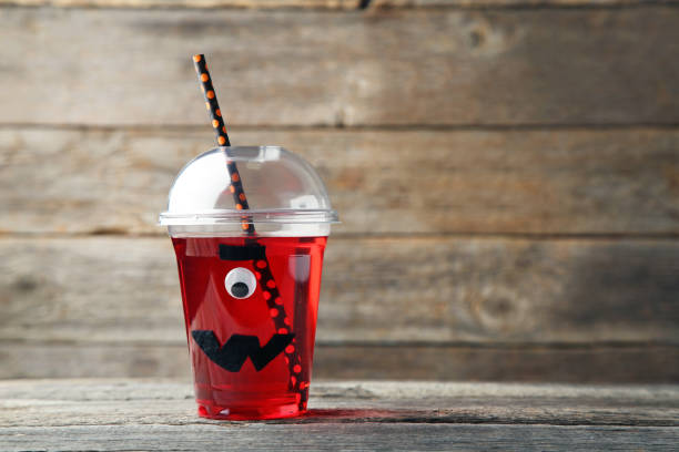 istock Halloween cocktail in plastic cup on grey wooden table 1036003056