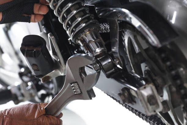 Cropped view of Mechanic using a wrench on a motorcycle Cropped view of Mechanic using a wrench on a motorcycle on white background bike workshop stock pictures, royalty-free photos & images