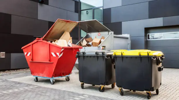 Red dumpster, recycle waste and garbage bins near new office building
