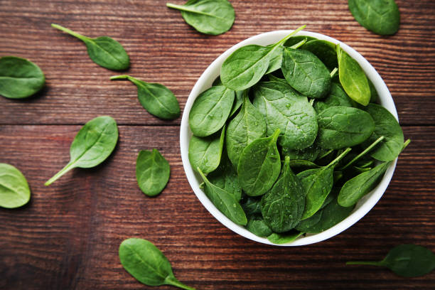 istock Spinach leafs in bowl on brown wooden table 1036023864