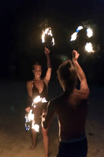 Beautiful, young man and woman performing fire dance on the beach.
