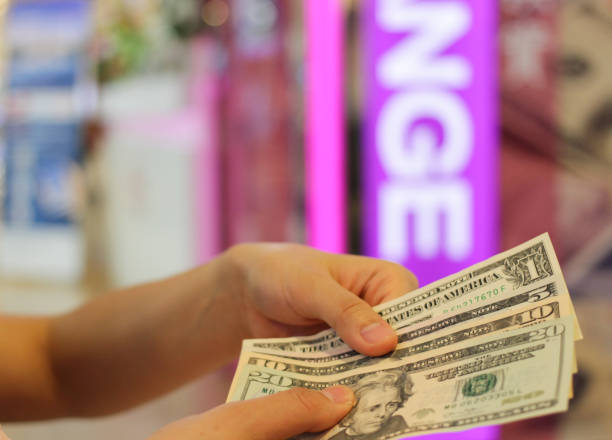 istock hand holding us dolla money for exchange and blur background. 1036030408