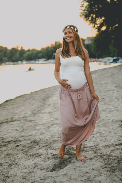 istock Young pregnant woman walking by the river 1036041442