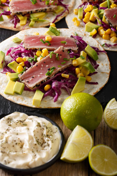 istock Delicious food: fish tortillas with tuna, sesame, corn, cabbage and avocado close-up. vertical 1036052658